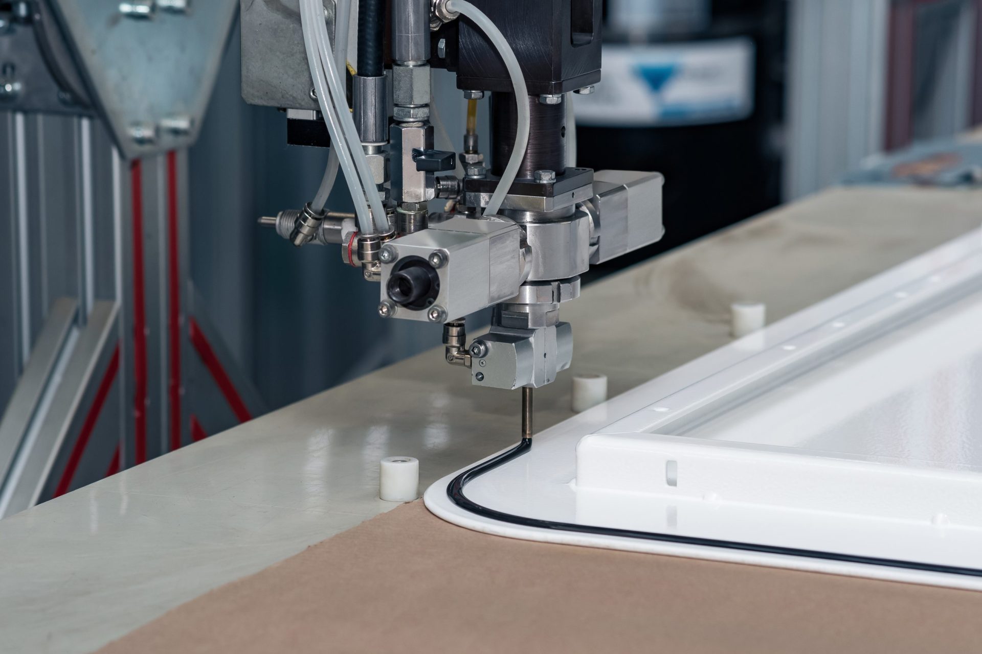 industrial robotic dosing dispenser machine applies a hardening sealant to the metal door blank